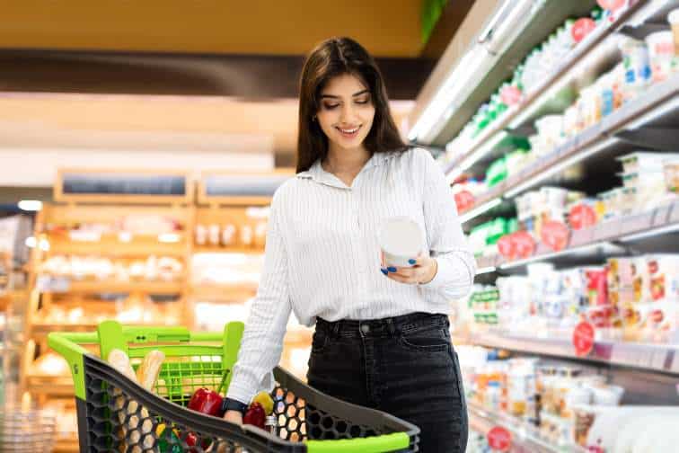 Woman grocery shopping to illustrate that consumer stables stocks that can outperform in a recession.